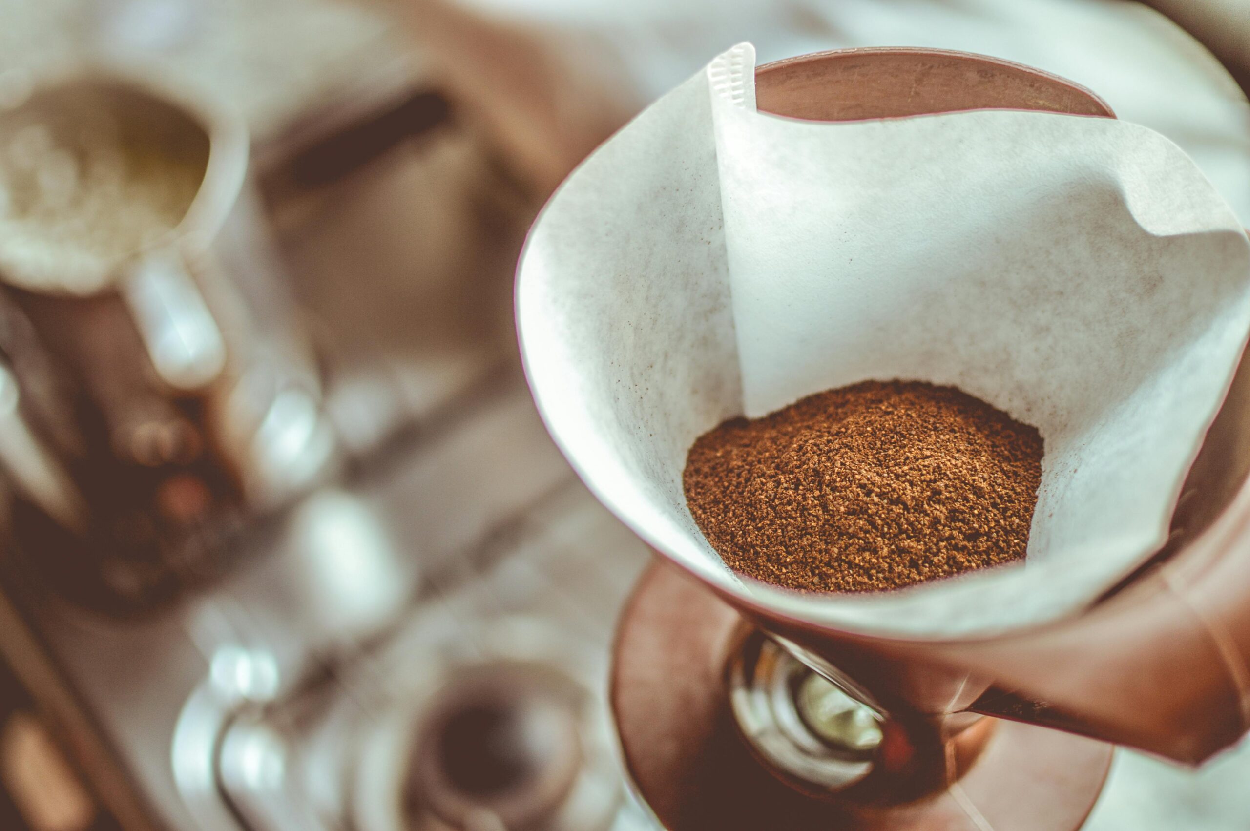 A close-up shot of freshly ground coffee inside a paper filter placed in a pour-over coffee dripper, ready for brewing