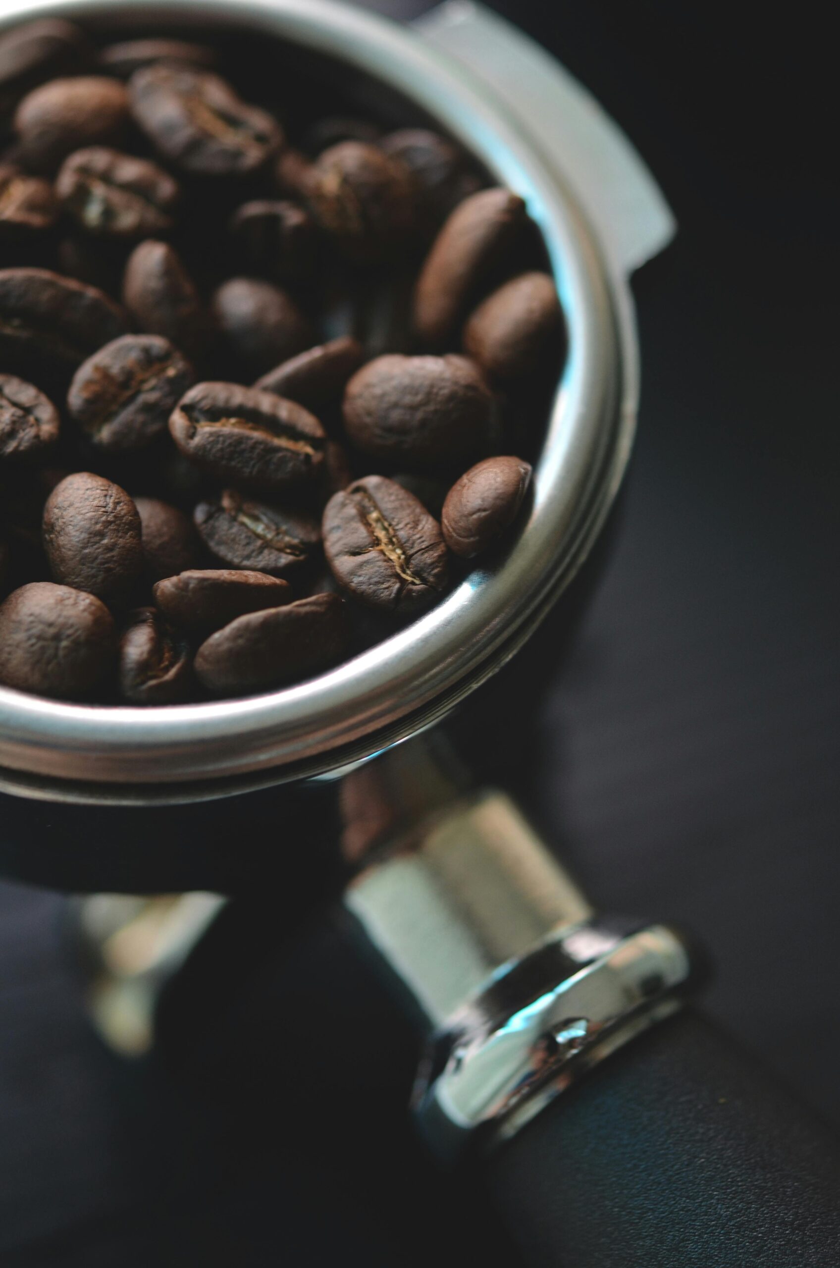 A portafilter filled with whole roasted coffee beans, ready to be used for brewing espresso
