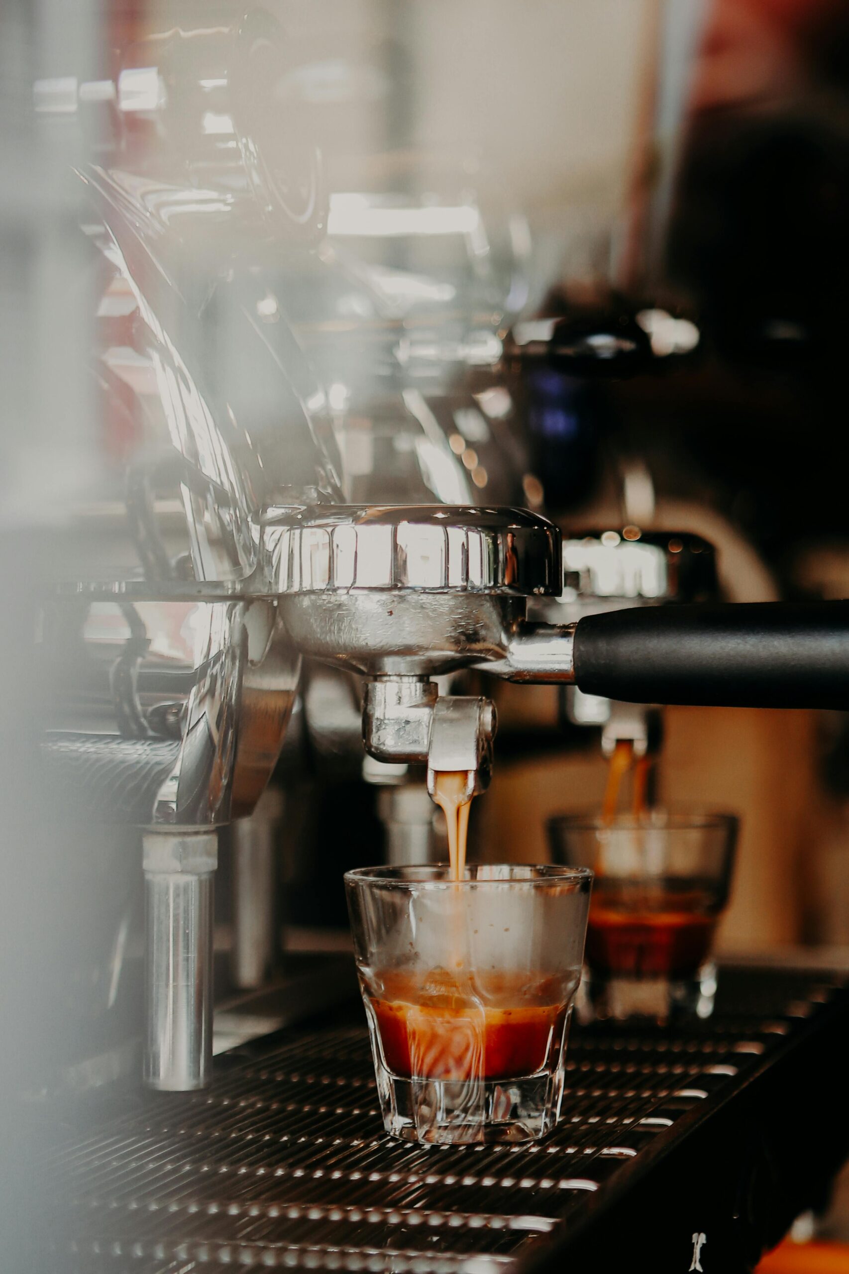 A beautifully crafted latte with a delicate leaf latte art design served in a pastel green cup, placed on a home espresso machine